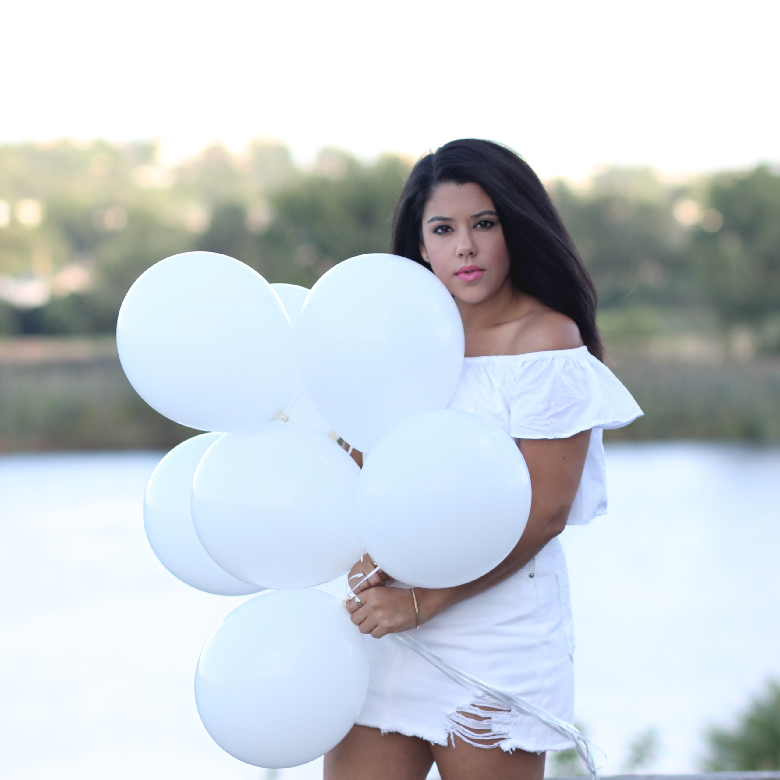 style blogger naty michele wearing all white and holding white balloons