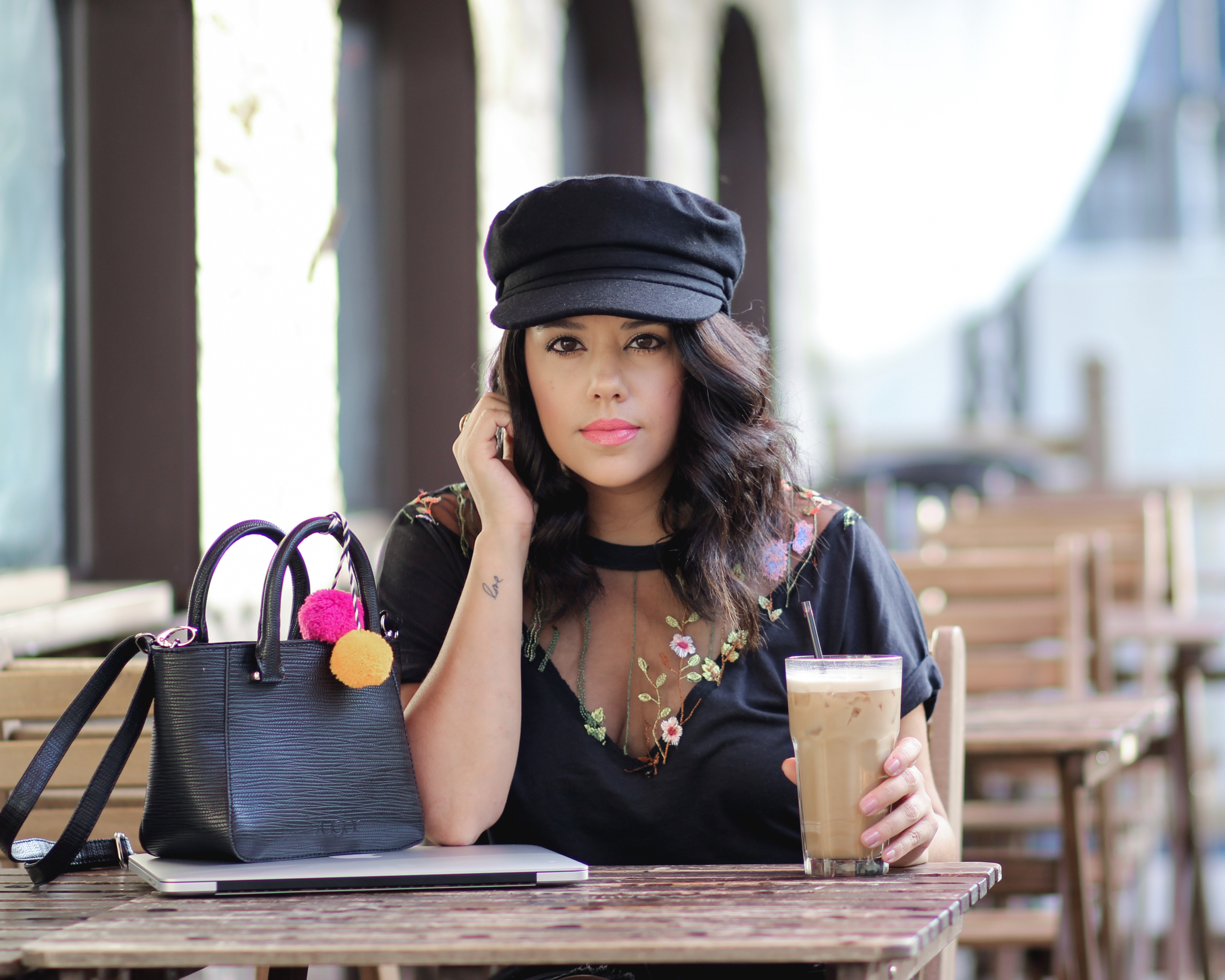 lifestyle blogger naty michele sitting down in a cabbie hat with a latte