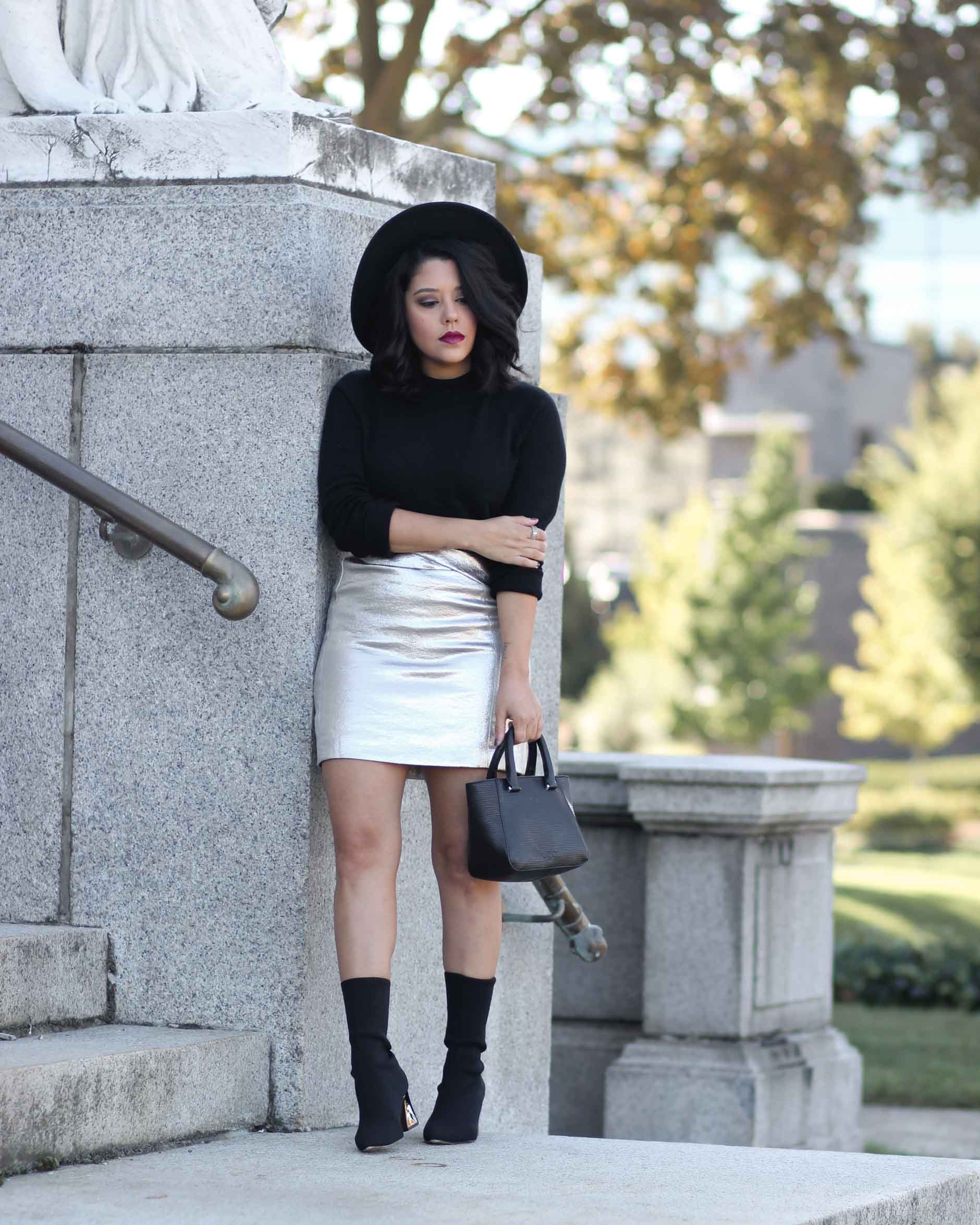 lifestyle blogger naty michele wearing a silver skirt and black sock boots