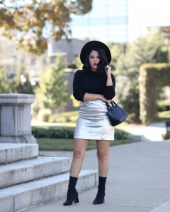 lifestyle blogger naty michele wearing a silver skirt with a black sweater and black sock boots