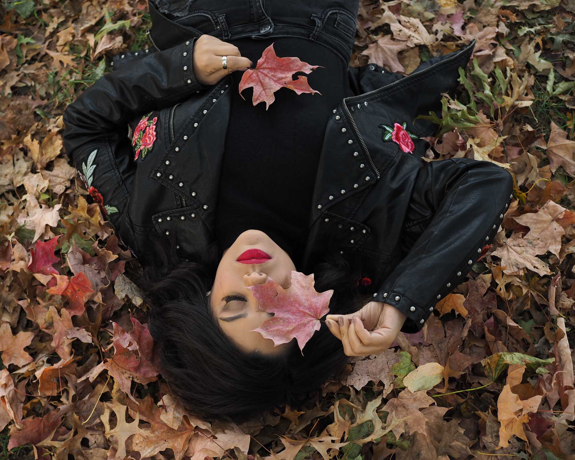 lifestyle blogger naty michele laying in a pile of leaves