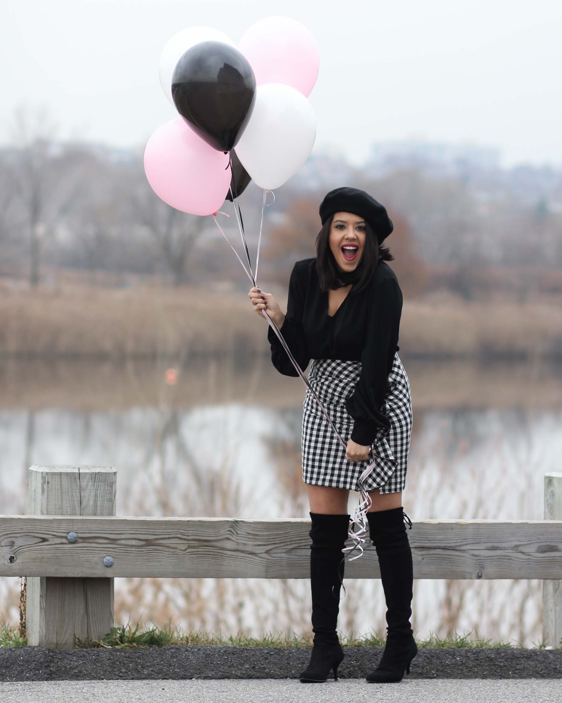 lifestyle blogger naty michele wearing otk boots with a beret and gingham skirt holding balloons 