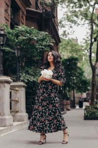 naty michele in a floral dress holding white roses