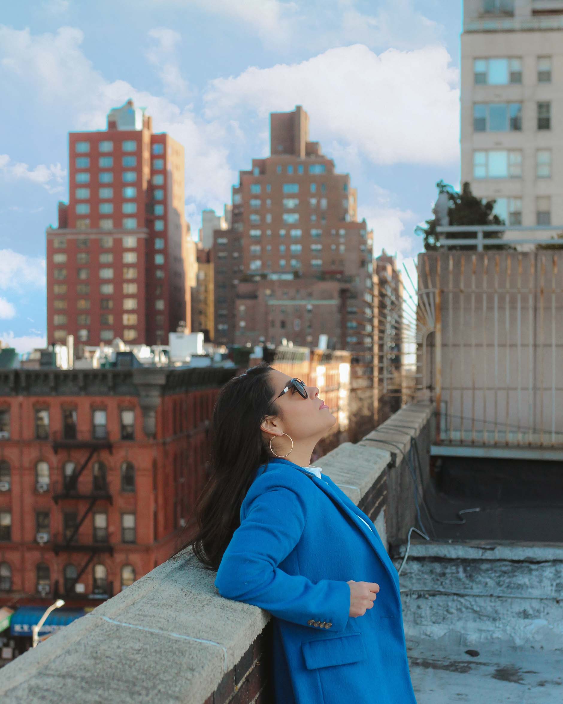 naty michele wearing a blue coat on a new york city rooftop